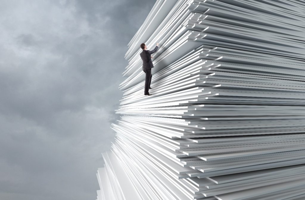 man climbing a big pile of papers